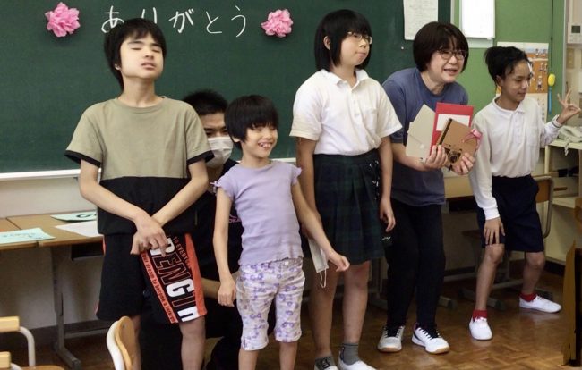 小学部の5・6年生とお送りする先生とみんなで記念撮影。背景の黒板には「ありがとう」という文字がお花飾りに囲まれています。